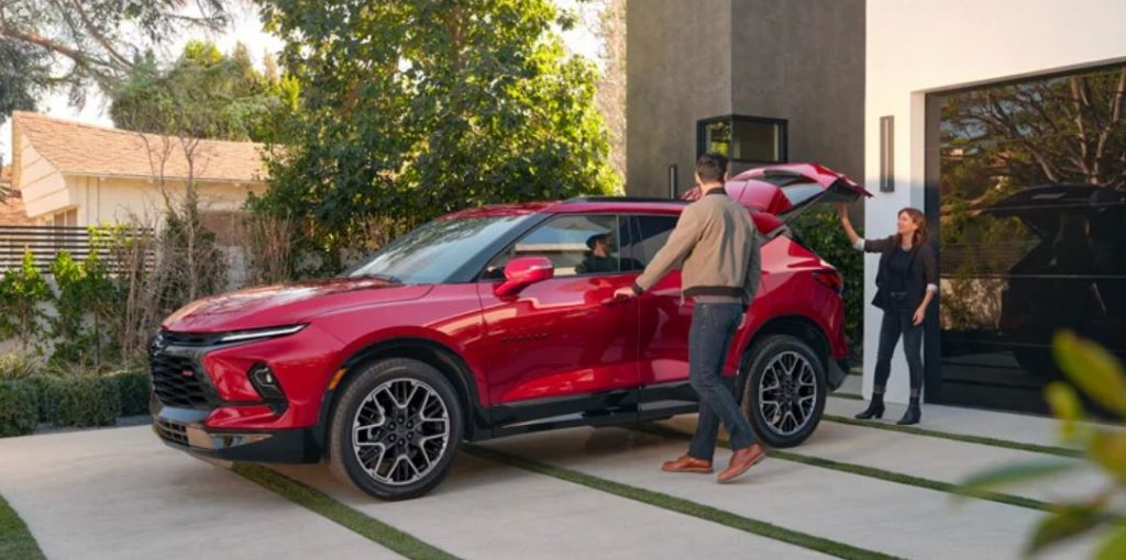 A red 2023 Chevrolet Blazer parked on a driveway and the owner family is prepping the car to get in.