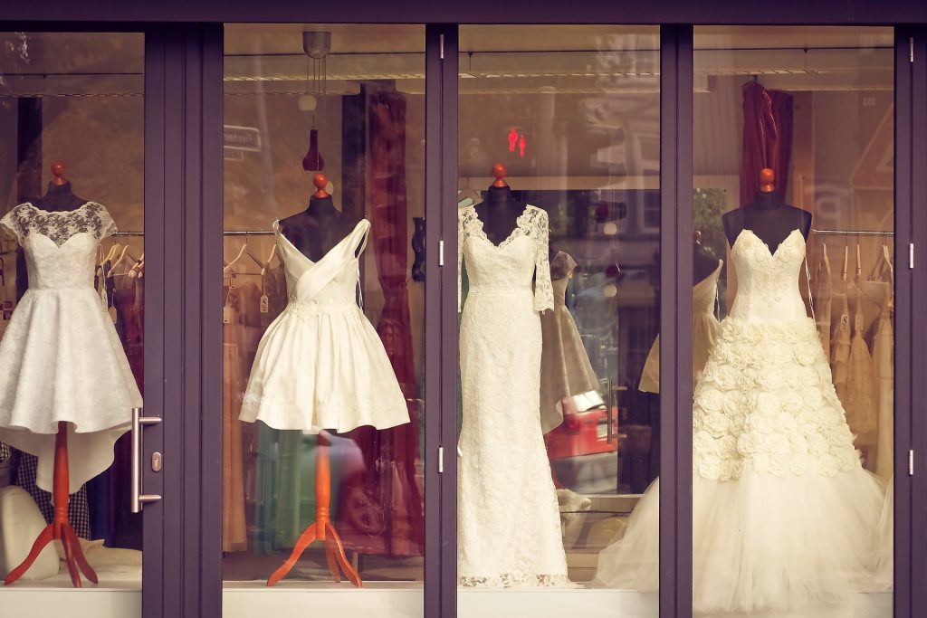 The front of a bridal shop with dresses in the window.