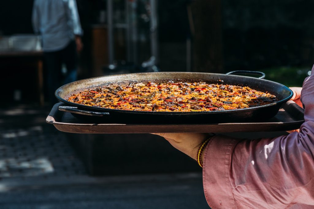 A paella being brought to the table.