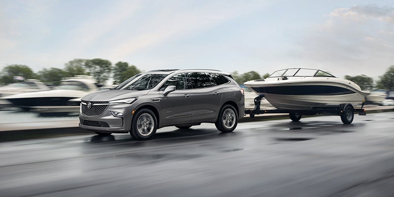 A silver 2023 Buick Enclave towing a boat.