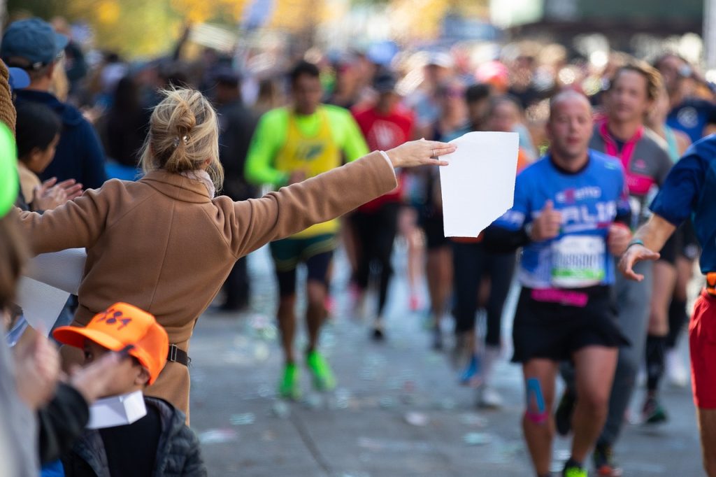 A woman handing a towel to marathon runners.