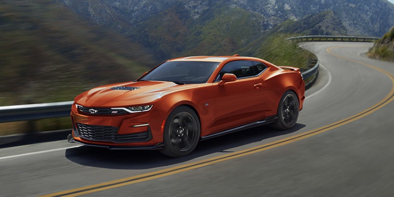 An orange 2024 Chevy Camaro driving down a windy mountain highway.